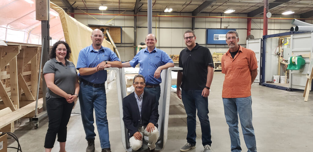 Habib Dagher (center front) and Bill Davids (right) from the University of Maine and (L-R) Carmala Buzzell, Wendell Harriman, Ken Sweeney, and Tim Kenerson from AIT Bridges with a CT Girder developed in the UMaine Composites Center.