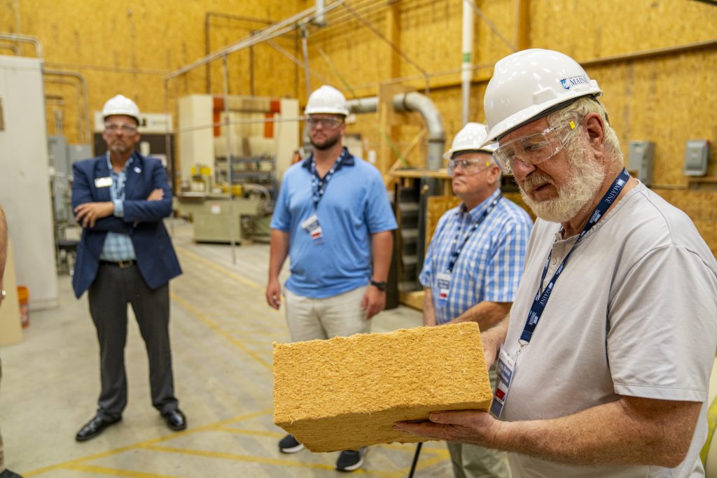 A man in a hard hat holding a block of wood fiber insulation